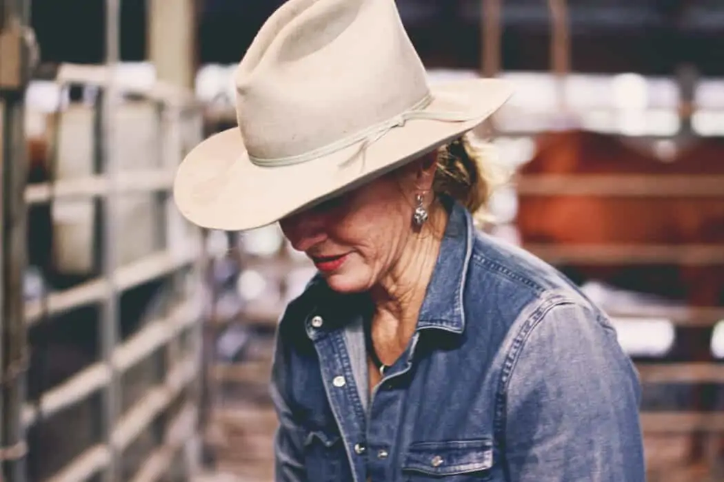 Renee Strickland standing in her horse barn wearing a cream cowboy hat.
